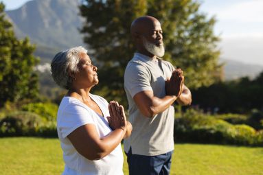 A serene older couple meditate outside knowing that they are financially prepared to thrive in retirement.